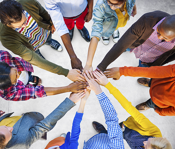 Photo of people in a circle with their hands in the middle