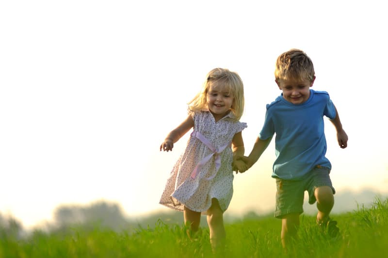 Little boy and girl running on the field